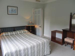ein Schlafzimmer mit einem Bett, einer Kommode und einem TV in der Unterkunft Neidin House in Kenmare