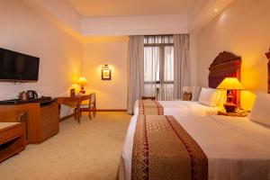 a hotel room with two beds and a desk at Royale Chulan Kuala Lumpur in Kuala Lumpur