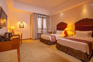 a hotel room with two beds and a television at Royale Chulan Kuala Lumpur in Kuala Lumpur
