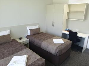 a hotel room with two beds and a desk at Naracoorte Hotel Motel in Naracoorte