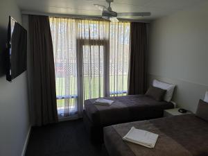 a hotel room with two beds and a window at Naracoorte Hotel Motel in Naracoorte