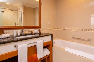 a bathroom with a sink and a tub and a mirror at Royale Chulan Kuala Lumpur in Kuala Lumpur