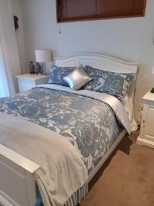 a bedroom with a bed with a blue and white comforter at Maples on Harewood in Christchurch