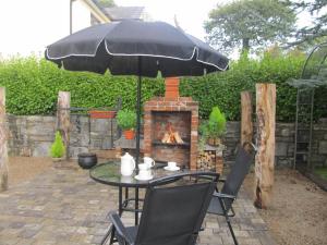 a table with an umbrella and a fireplace at Neidin House in Kenmare +23 photos