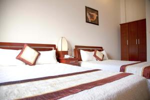 ダナンにあるHoang Thuy Sinh Hotelのベッド2台と鏡が備わるホテルルームです。