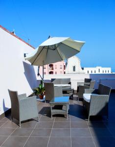 un patio con mesas, sillas y una sombrilla en Bed And Breakfast Charming House, en Barletta
