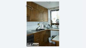 cocina con armarios de madera, fregadero y ventana en Ferienwohnung harZauber, en Braunlage