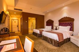 a hotel room with two beds and a table at Royale Chulan Kuala Lumpur in Kuala Lumpur