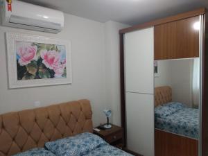 1 dormitorio con cama y armario con espejo en Apto Vista Atlântico com 2 quartos com Ar Cond Wi-Fi TV SMART e Área de lazer, en Itapema