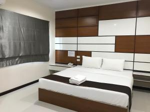 a bedroom with a bed with white sheets and wood panels at TTT Hotel in Hat Yai