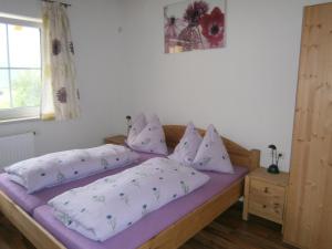 um quarto com uma cama com lençóis e almofadas roxos em Landgut Feuersang em Sankt Veit im Pongau