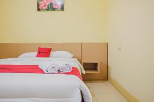 1 dormitorio con 1 cama con toallas rojas y blancas en RedDoorz near RS Imanuel Lampung, en Lampung