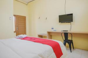 a bedroom with a bed and a desk and a television at RedDoorz near RS Imanuel Lampung in Lampung