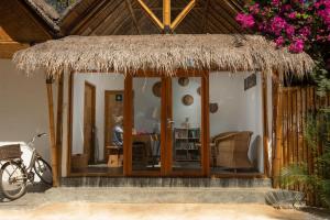 a house with a straw hut with a bike parked outside at Sea Breeze Villas - Gili Air in Gili Air