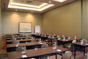 una sala de conferencias con mesas, sillas y una pantalla en Hotel Gunawangsa MERR en Surabaya