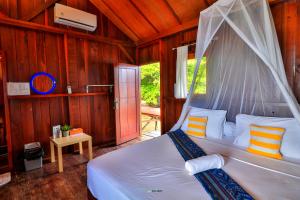 Schlafzimmer mit einem Bett mit Moskitonetz in der Unterkunft Hamueco Dive Resort Raja Ampat in Rabia
