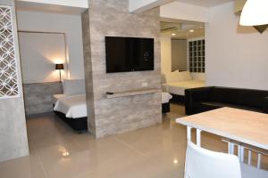 チェンマイにあるLoyy Hotelのソファ付きの壁にテレビが備わるホテルルームです。