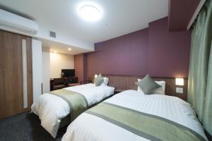 a hotel room with two beds and a purple wall at Myoujin-no-Yu Dormy Inn Premium Kanda in Tokyo