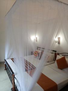 a bedroom with two beds with mosquito netting at White House Ella in Ella