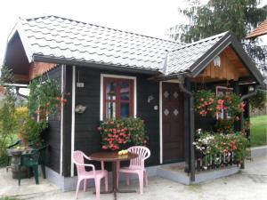 a small black house with pink chairs and a table at House Ilija Hodak in Seliste Dreznicko