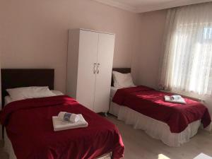a bedroom with two beds with red sheets and a cabinet at Ayberk Pansiyon in Çanakkale