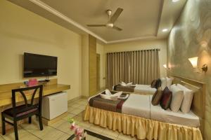 a hotel room with a bed and a flat screen tv at Vishwaratna Hotel in Guwahati