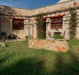 a stone house with a table and chairs in the yard at Villa in Salento in Lecce