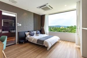 Un dormitorio con una cama y una ventana grande. en Ocean Villa Fuchaku Okinawa, en Fuzuchi