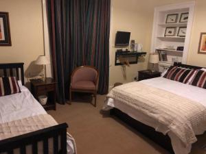 a bedroom with two beds and a chair and a desk at Easter Garth Guest House in Helensburgh
