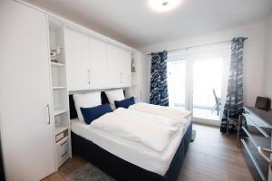 een slaapkamer met een groot wit bed met blauwe kussens bij Attraktive Apartments im "Port Marina" in Bremerhaven