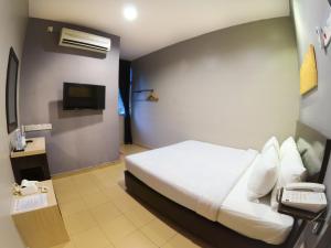 Habitación de hotel con cama y teléfono en JV Hotel @ Bandar Tasek Mutiara en Simpang Ampat