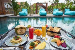 uma mesa com pratos de comida ao lado de uma piscina em Kubu Tropis em Ubud