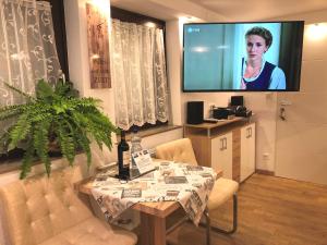 a living room with a table and a flat screen tv at Ferienwohnung Apartment Dettum mit eigenem Bad, Kochnische und Wintergarten in Dettum