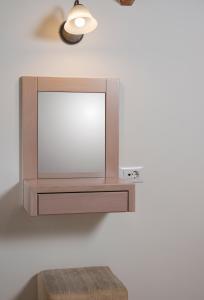 a mirror hanging on a wall with a wooden stool at Pantanassa Villas in Agia Marina Nea Kydonias
