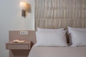 a bed with white pillows and a night stand with a lamp at Pantanassa Villas in Agia Marina Nea Kydonias
