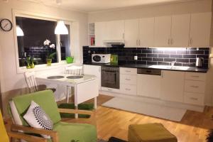 a kitchen with white cabinets and a green chair at Apartment close to Aibel Haugesund in Haugesund