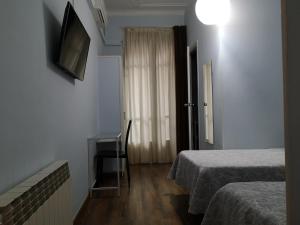 a room with two beds and a desk and a window at Hostal Lesseps in Barcelona