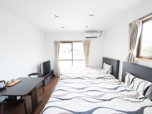 - une chambre avec un lit, un bureau et une fenêtre dans l'établissement Maruka石垣島, à Ishigaki
