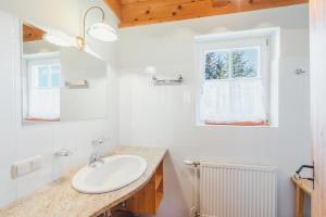 a white bathroom with a sink and a window at Alpine Cabin in Klippitztorl