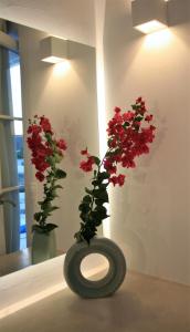 a vase with red flowers in a room at Mykonos Moussa in Agios Ioannis Mykonos