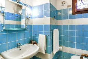 a blue tiled bathroom with a sink and a mirror at Colonna Country Club in Porto Cervo