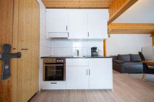 una cucina con mobili bianchi e un divano in una stanza di Haus Pickelschmiede a Saas-Grund