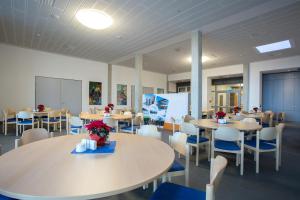 a dining room with tables and chairs and a board at Sportpark Rabenberg in Breitenbrunn