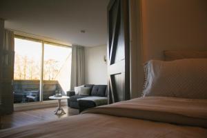 una camera da letto con un letto, un divano e una finestra di T'hûs bed & breakfast a Katlijk
