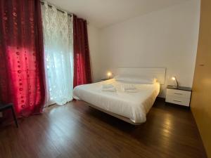 1 dormitorio con cama blanca y cortinas rojas en P&C Dolsa, en Pas de la Casa