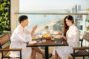 a man and two women sitting at a table eating food at Paris Deli Danang Beach Hotel in Danang
