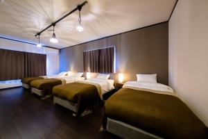 a row of four beds in a room with lights at ID-STAY河口湖Ⅲ in Fujikawaguchiko