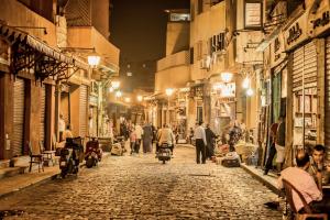 un grupo de personas caminando por una calle por la noche en Le Riad Hotel de Charme, en El Cairo