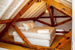 a bed in the middle of a loft with wooden ceilings at Casa Gil Vicente in Almada