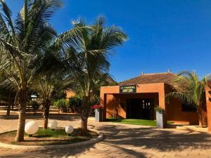 a building with palm trees in front of it at La Taniere Villa Metsu in Saly Portudal